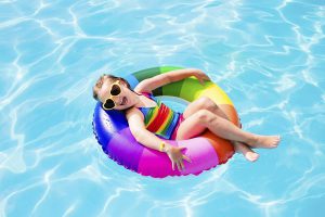 Niña en la piscina en el verano con lentes de sol para protegerse de los rayos uv