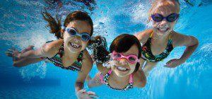Tres niñas nadando con protección con lentes para nadar en el verano